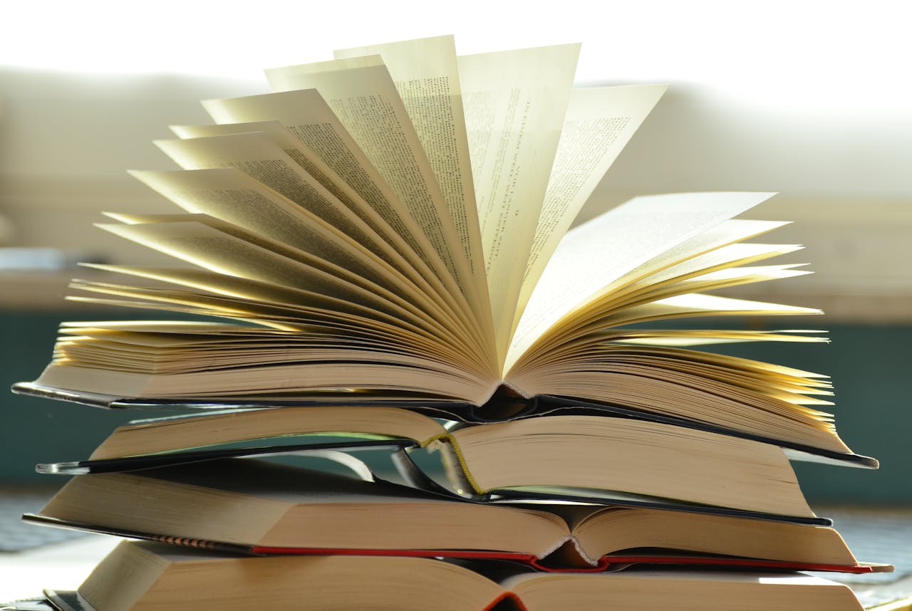 pexels photo 8447618 A close-up of a stack of open books with pages fanned out, capturing a study atmosphere.